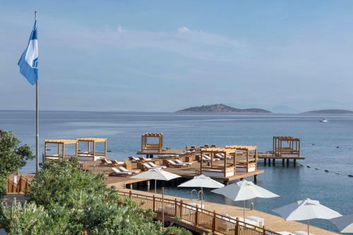 a beach with chairs and umbrellas in the water at Susona Bodrum, LXR Hotels & Resorts in Bodrum City