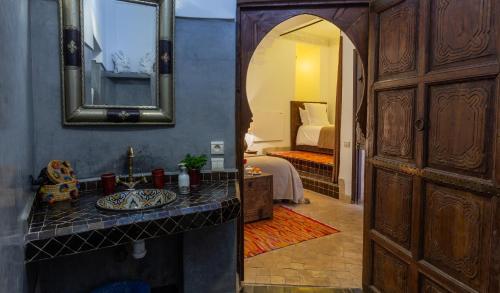 a bathroom with a sink and a mirror and a bedroom at Les Sources Berbères Riad & Spa in Marrakesh