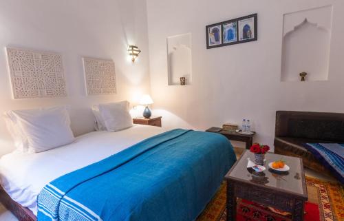 - une chambre avec un grand lit et une couverture bleue dans l'établissement Les Sources Berbères Riad & Spa, à Marrakech