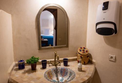 bagno con lavandino e specchio di Les Sources Berbères Riad & Spa a Marrakech