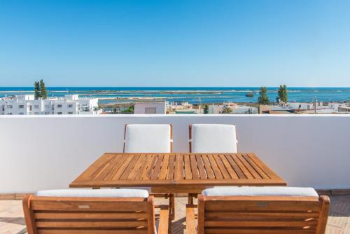 a wooden table and chairs with a view of the ocean at Casa do Ser in Fuzeta