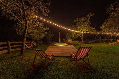 two chairs and a table in a yard at night at Hedgehog's Home in Korenica