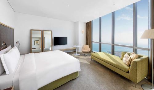 a bedroom with a large white bed and a couch at Conrad Abu Dhabi Etihad Towers in Abu Dhabi