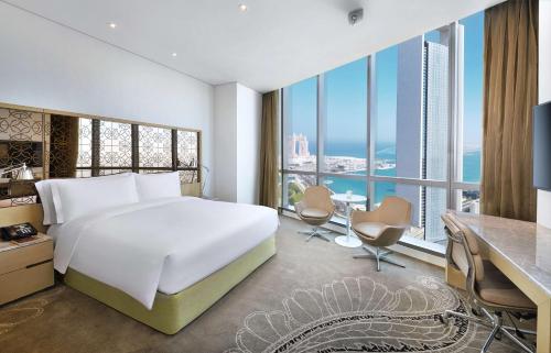 a bedroom with a bed and a desk and a large window at Conrad Abu Dhabi Etihad Towers in Abu Dhabi