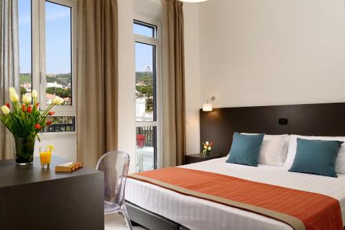 a hotel room with a bed and a desk and a window at Villa delle Palme in Santa Marinella