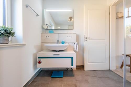 a bathroom with a white sink and a mirror at Haus Dünenweg Whg 2 in Hörnum