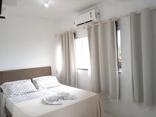 a bedroom with a bed with white sheets and a window at #Tribo Suítes no alto do morro in Morro de São Paulo