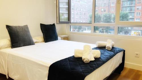 een slaapkamer met een groot bed en handdoeken bij Deustown Apartamentos in Bilbao
