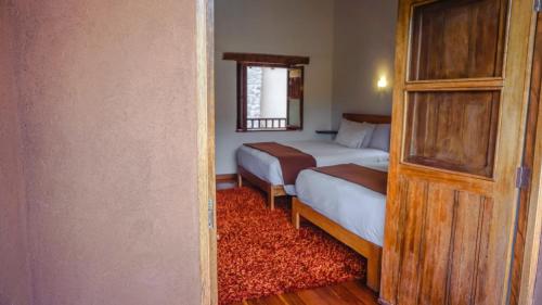 a small bedroom with two beds and a window at Lizzy Wasi Urubamba in Urubamba