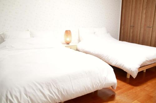 two beds in a room with white sheets and a lamp at Chiba - House - Vacation STAY 87410 in Chiba