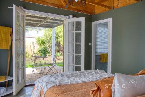 a bedroom with a bed and a door to a patio at Studio on Bridport in Daylesford