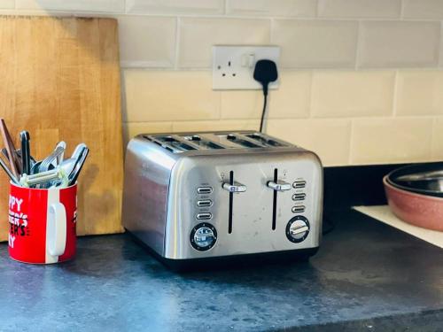 a toaster sitting on a counter next to a cup of utensils at Jey's Flat in Liverpool