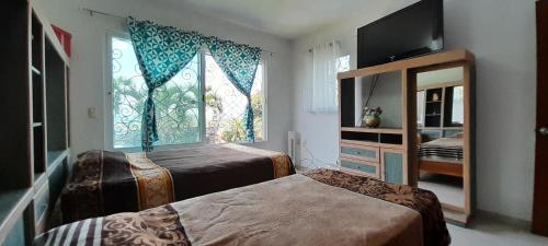 a bedroom with two beds and a window and a mirror at Casa con alberca privada y agradable jardín in Oaxtepec