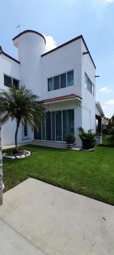 a white house with a palm tree in front of it at Casa con alberca privada y agradable jardín in Oaxtepec