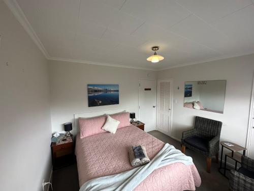 ein Schlafzimmer mit einem rosa Bett und einem Stuhl in der Unterkunft Glamis Ave Shared Home B&B in New Plymouth