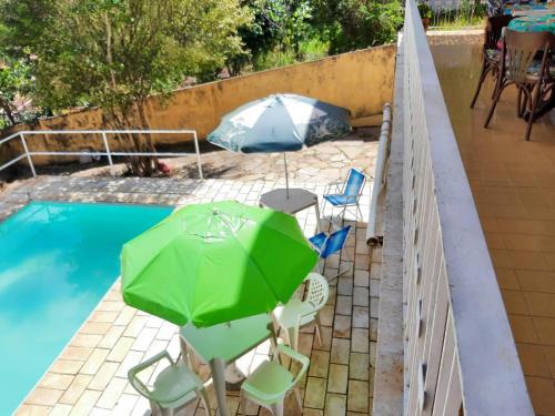a patio with an umbrella and chairs and a pool at hospedagens regina in Águas de Lindóia