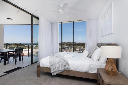 a white bedroom with a bed and a table with chairs at Solaris 505 in Forster
