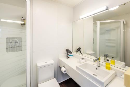 a white bathroom with a sink and a mirror at The Ashley Hotel Greymouth in Greymouth