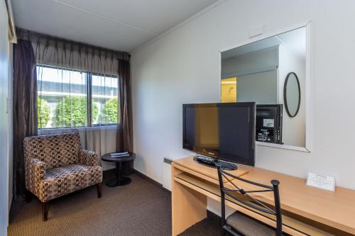 a room with a desk with a television and a chair at The Ashley Hotel Greymouth in Greymouth