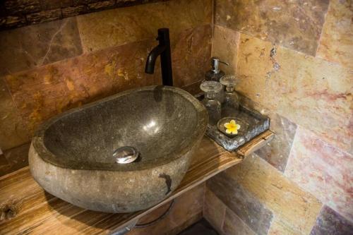 a bathroom with a stone sink with a faucet at Aryasa Villa 1BR Private Pool Villa Ubud in Ubud
