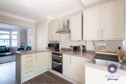 a white kitchen with white cabinets and a sink at The Old Office in Royal Tunbridge Wells