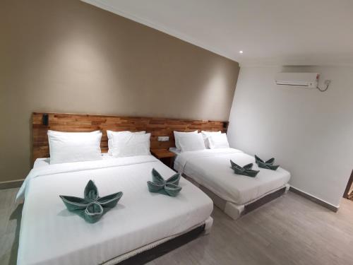dwa łóżka z zielonymi kwiatami na nich w pokoju w obiekcie Hemingway Cottage 海明威度假屋 w mieście Semporna