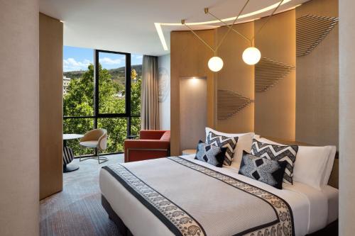 um quarto com uma cama e uma grande janela em Paragraph Freedom Square, a Luxury Collection Hotel, Tbilisi em Tbilisi