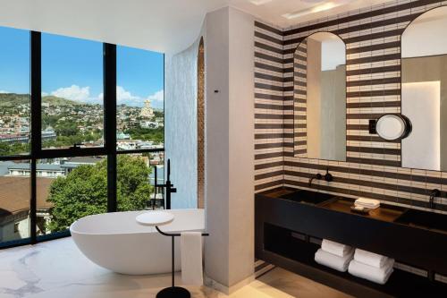 Paragraph Freedom Square, a Luxury Collection Hotel, Tbilisi في تبليسي: حمام مع حوض استحمام و نافذة كبيرة