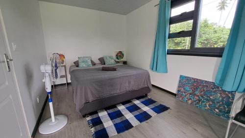 Teahupoo的住宿－TAHITI ITI - Bungalow O Spot Teahupoo，一间卧室配有一张带蓝色窗帘的床和一扇窗户