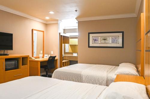 Habitación de hotel con 2 camas y escritorio en Days Inn by Wyndham San Francisco S/Oyster Point Airport en South San Francisco