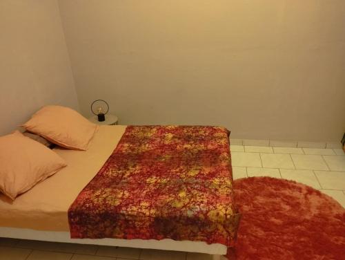 a bedroom with a bed with a rug on it at chambre climatisée avec bureau in Saint-Joseph