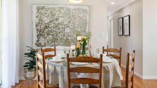a dining room with a table with chairs and a painting at Bluebird Cottage in Bowral