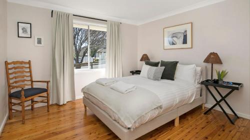 Un dormitorio con una cama y una silla y una ventana. en Bluebird Cottage, en Bowral