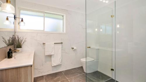 Un baño con inodoro y ducha de cristal. en Bluebird Cottage, en Bowral
