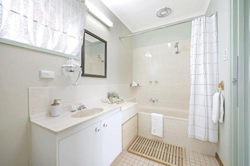 a white bathroom with a sink and a shower at City Heart Motel Warrnambool in Warrnambool