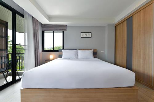 a bedroom with a large white bed and a balcony at Raweewan Residence hotel in Bangkok