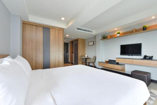 a bedroom with a large white bed and a flat screen tv at Raweewan Residence hotel in Bangkok