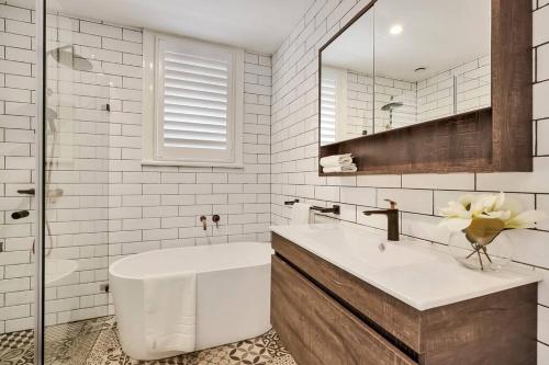 uma casa de banho com uma banheira, um lavatório e um espelho. em Sydney CBD Waterview apartment56 em Sydney