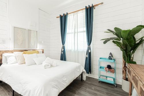 a bedroom with a bed with white sheets and blue curtains at Vanderbilt Beach Studio in Naples