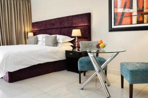 a bedroom with a bed and a glass table and chair at Vredenburg Boutique Lodge in Vredenburg