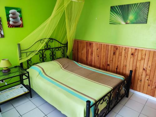 a bedroom with a bed with a green wall at Gîtes TAINACO in Vieux-Habitants