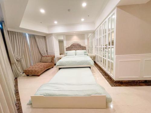 een slaapkamer met 2 bedden en een stoel. bij Elegance penthouse in Surabaya