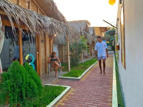 a man and woman walking down a brick sidewalk at Puerto Bamboo in Máncora