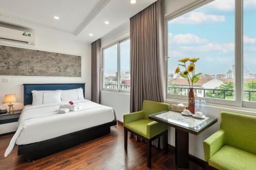 um quarto com uma cama, uma mesa e cadeiras em Golden Sun Hotel em Hanói