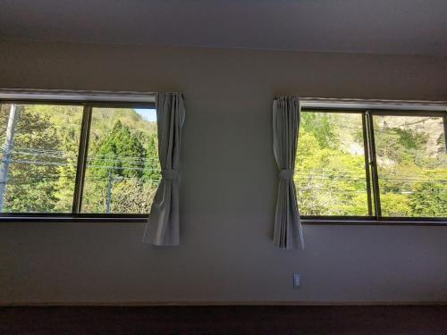 two windows in a room with a view of trees at LOOP-shiso 宍粟市BBQとサウナでととのう天空回廊にたたずむ貸別荘 in Shiso