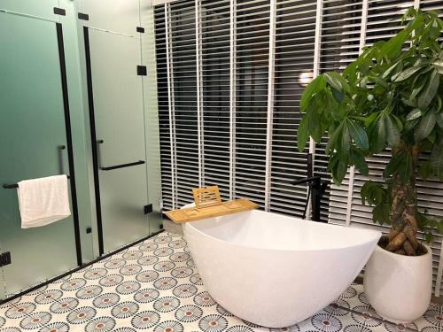 ein Badezimmer mit einer weißen Badewanne und einer Topfpflanze in der Unterkunft AnAn Sweethome Penhouse Duplex near Bát Tràng in HÆ°ng YÃªn