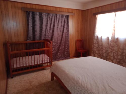 a bedroom with a crib and a window at Surfside two-bedroom holiday upstairs in Batemans Bay