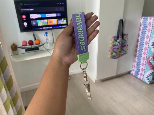 a hand holding a purple remote control with a pair of keys at Sirena Beach Chic Staycation at Azure Paris Beach Club in Manila