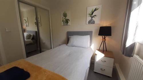 a small bedroom with a white bed and a lamp at Carvetii - Clark House - Spacious ground floor flat in Rosyth
