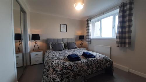 a bedroom with a bed with two blue bags on it at Carvetii - Clark House - Spacious ground floor flat in Rosyth